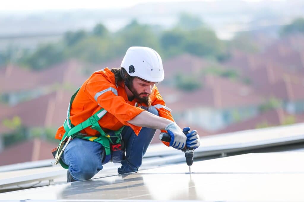 Workers Installing Solar Panels on warehouse Roof.